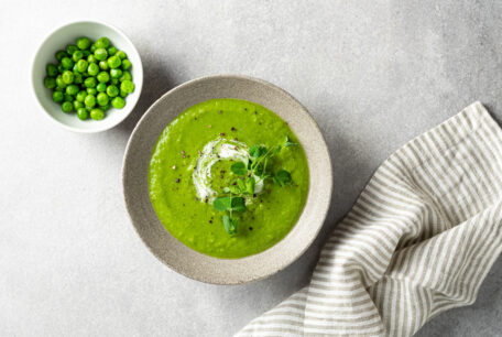 Thai Green Pea Soup garnished with pea shoots on a grey background